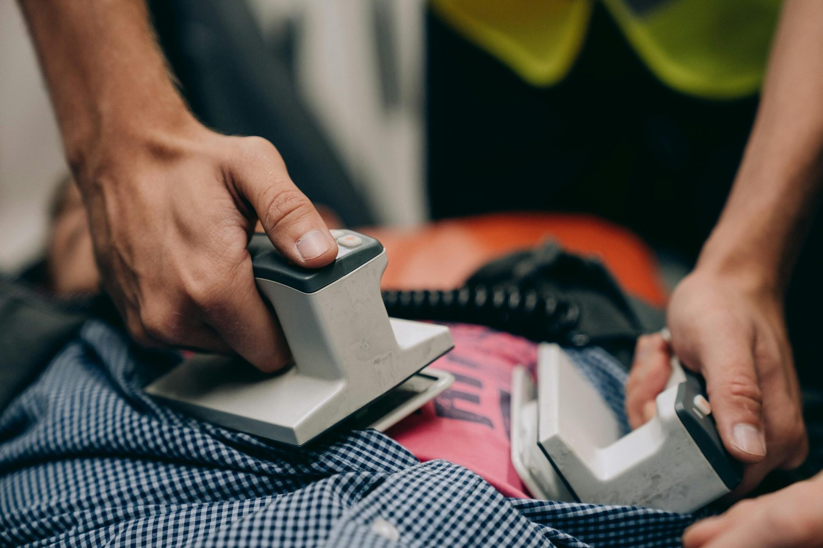 Hands using a defibrillator on a patient during an emergency CPR situation.